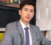 Professional businessman in a gray suit working at a desk with a notebook and pen.